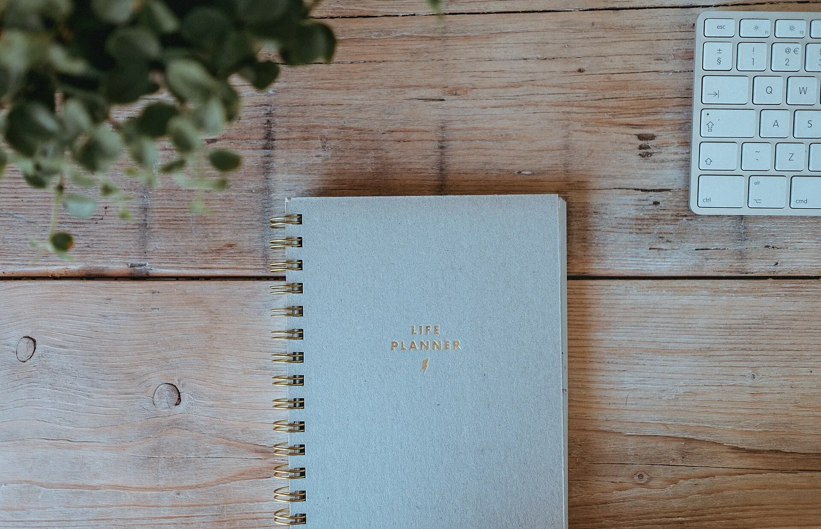 Buku agenda di atas meja kayu di samping papan ketik