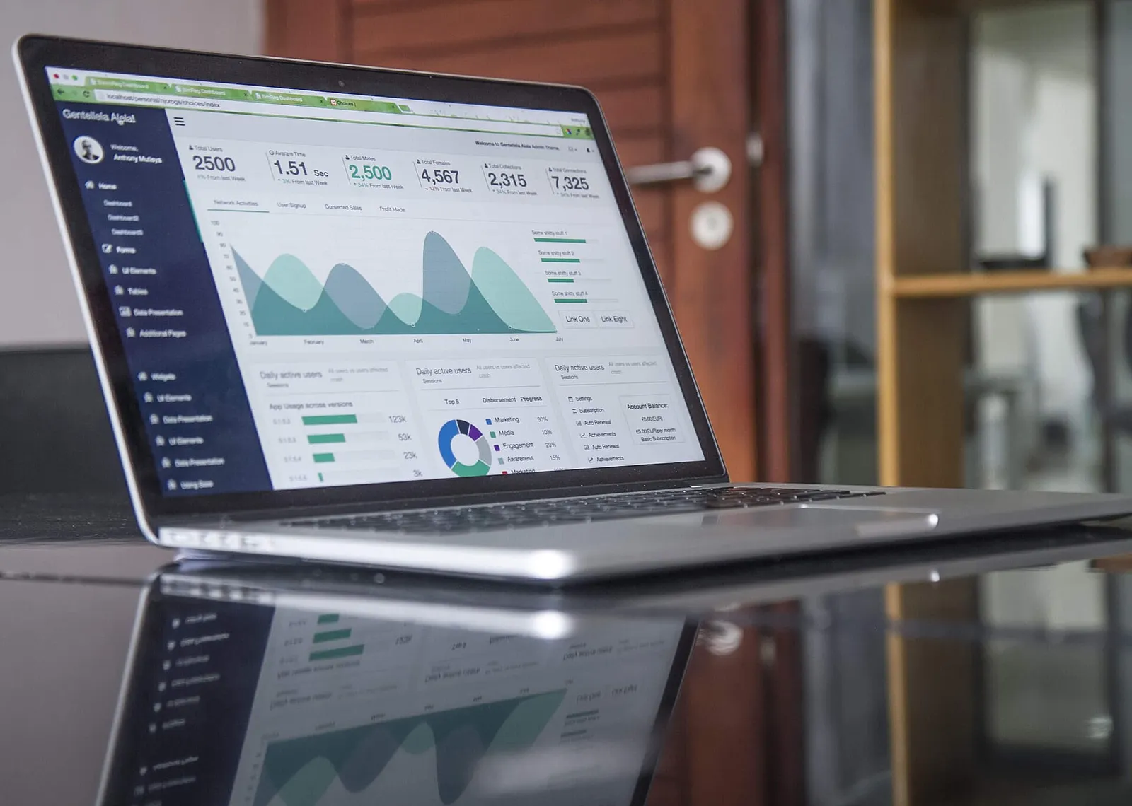 Laptop di atas meja menampilkan grafik statistik