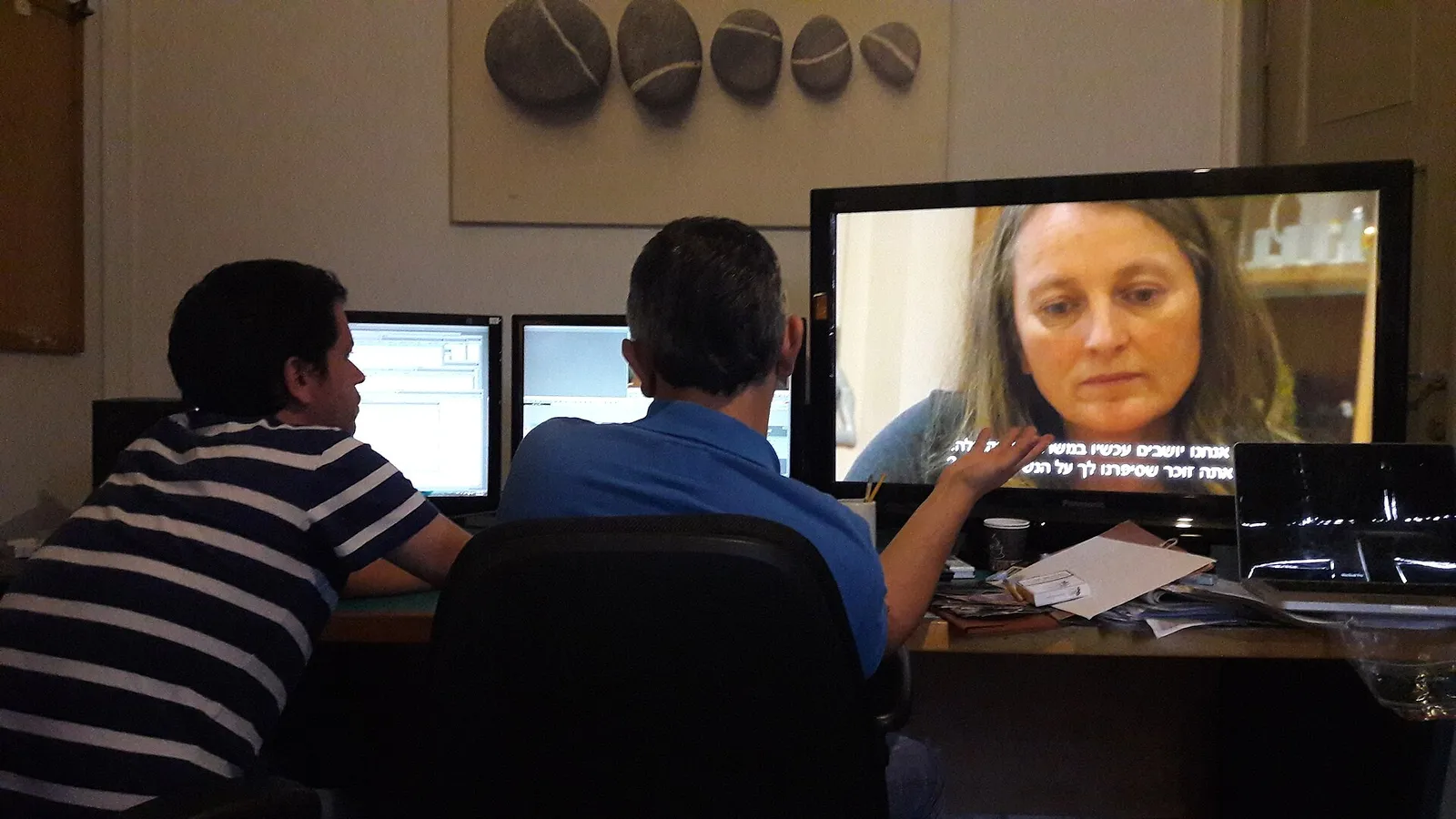 Dua orang menyunting video di depan beberapa layar monitor